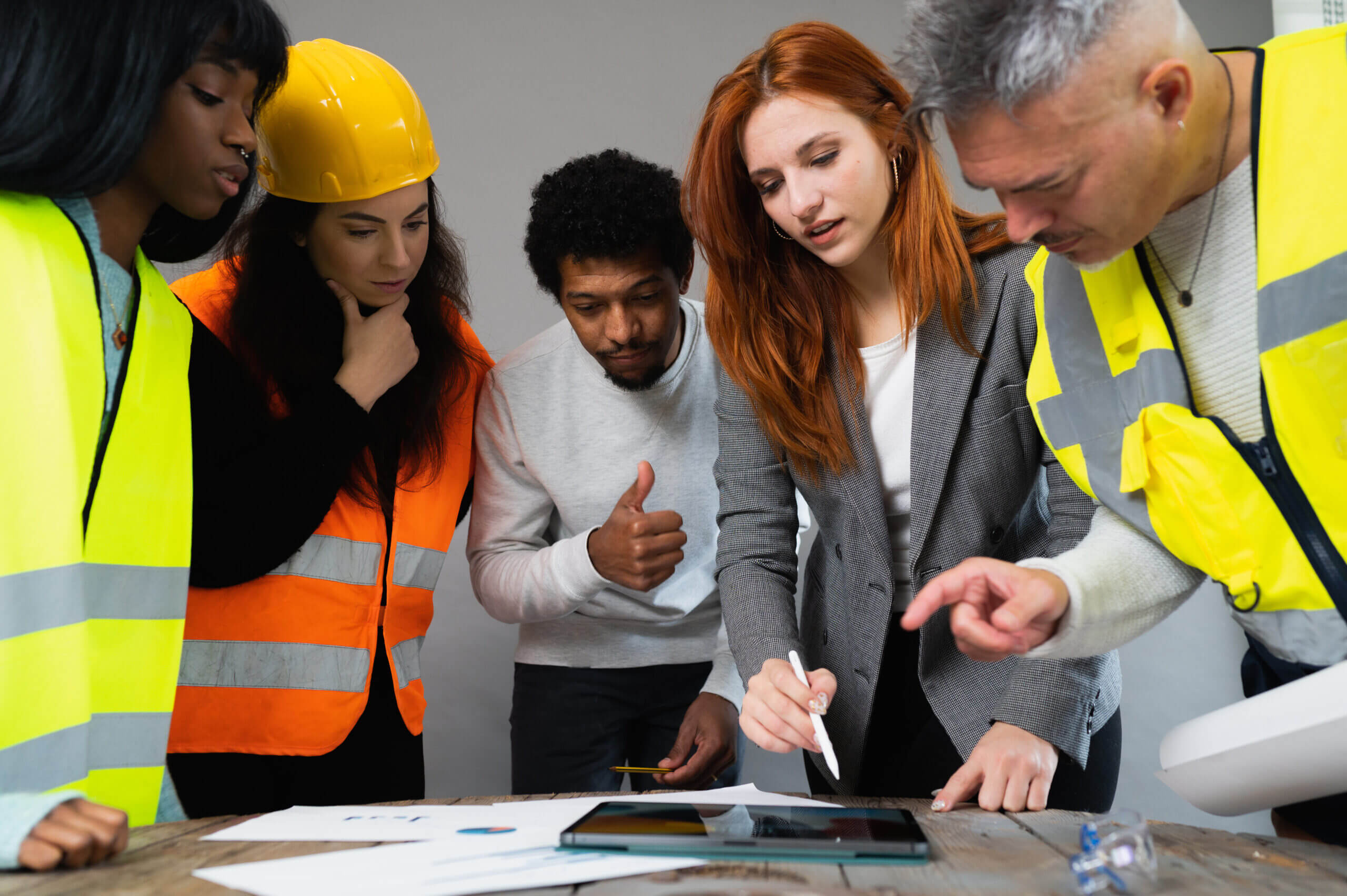 Group of five multiracial people working in a construction. Architects examining the project in the office.